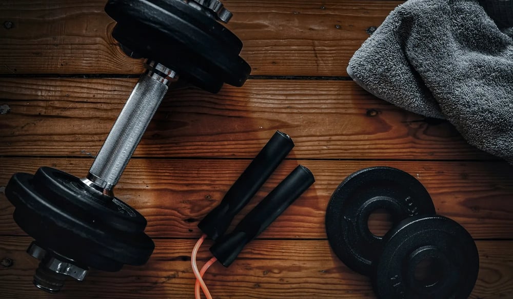 Dumbbell, skipping rope and towel on a wooden table